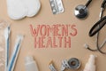 Flat lay composition with sanitary pads, pills near words Women`s Health on beige background