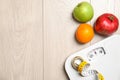 Flat lay composition with scales, measuring tape, fruits and space for text on wooden background.