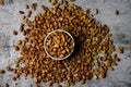 Flat lay composition of shelled golden peanuts in a white bowl on a textured background