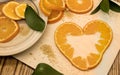 flat lay composition with sliced oranges in heart shape and green leaves on wooden light cutting board. Flat lay Top view