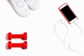 Flat lay composition with sneakers, headphones, mobile phone and red dumbbells on white background.