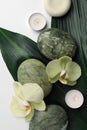 Flat lay composition with spa stones, green leaves and beautiful flowers on white table Royalty Free Stock Photo