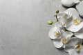 Flat lay composition with spa stones and orchid flowers on grey background Royalty Free Stock Photo