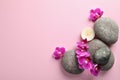 Flat lay composition with spa stones and orchid on pink background. Space for text Royalty Free Stock Photo