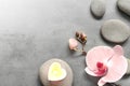 Flat lay composition with spa stones, orchid pink flower and heart on grey. Royalty Free Stock Photo