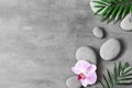 Flat lay composition with spa stones, orhid pink flower on grey background Royalty Free Stock Photo
