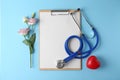 Flat lay  with stethoscope and flowers on light blue background, space for text. World health day Royalty Free Stock Photo