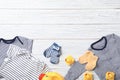 Flat lay composition with stylish baby clothes and toys on wooden background