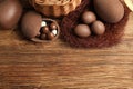 Flat lay composition with tasty chocolate eggs, wicker basket and decorative nest on wooden table. Space for text