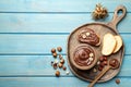 Flat lay composition with tasty chocolate paste and hazelnuts on light blue wooden table, space for text Royalty Free Stock Photo