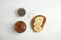 Flat lay composition with tasty toast, chocolate paste and chia seeds on white wooden background