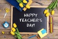 Flat lay composition for Teacher`s day on chalkboard with school supplies and tulip flowers on a rustic wooden table