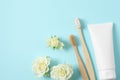 Flat lay composition with toothbrushes, toothpaste and flowers on turquoise background. Space for text