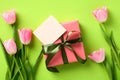 Flat lay composition with tulips and gift box with empty greeting card on green background. Happy Mother Day concept Royalty Free Stock Photo