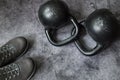 Flat lay composition of two kettlebells and a pair of grey sneakers.