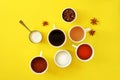 Flat lay composition of various cups of coffee, tea with sugar, cream and star anise on a bright yellow background.