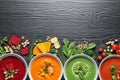 Flat lay composition with various soups, ingredients and space for text on wooden background