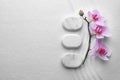 Flat lay composition of white stones and flowers on sand with pattern. Zen, meditation, harmony Royalty Free Stock Photo