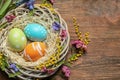 Flat lay composition of wicker nest with painted Easter eggs and flowers on wooden table Royalty Free Stock Photo