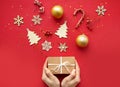 Flat lay composition. Woman hands and Christmas accessories and decorations on red background. top view, copy space