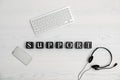 Flat lay composition with word SUPPORT, computer keyboard and headset on wooden background. Royalty Free Stock Photo