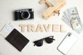 Flat lay composition with word TRAVEL, camera and passport on wooden background