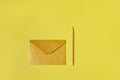 Flat lay composition of a yellow or golden envelope near a yellow wooden pencil isolated on a yellow background. Copy space Royalty Free Stock Photo