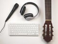 Flat lay of computer keyboard, headphones, microphone and acoustic guitar on white background. Online music lessons or musician Royalty Free Stock Photo