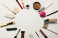 Flat lay of concealer,makeup brushes and bronzer over a white ba Royalty Free Stock Photo