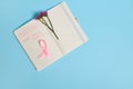 Flat lay composition of flower and pink ribbon, on opened notepad with inscriptions reminding of a medical check-up. October 1st,