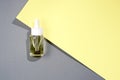 flat lay cosmetic transparent bottle with oil on grey and yellow background