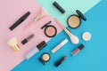 Flat lay cosmetics for makeup, brush, highlighter, concealer, makeup, lipstick, mascara, primer, blush on pink, blue and