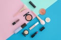 Flat lay Cosmetics for makeup, brush, highlighter, concealer, makeup, lipstick, primer, blush on pink, blue and mint tri