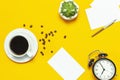 Flat lay cup black coffee, coffee beans, black alarm clock, pens, white cards, succulent on yellow background top view copy space Royalty Free Stock Photo