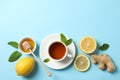 Flat lay. Cup of tea, lemon, ginger, mint, honey and dipper on blue background