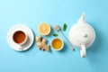 Flat lay. Cup of tea, teapot, lemon, ginger, mint, honey and dipper on blue background Royalty Free Stock Photo