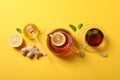 Flat lay. Cup of tea, teapot, lemon, ginger, mint, honey and dipper on yellow background Royalty Free Stock Photo