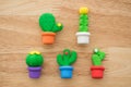 Flat lay of cute cactus in color pot toy eraser set on wooden background minimal style. Kid learning, development, love plant