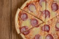 Flat lay pepperoni pizza isolated on rustic wooden background. Pizza salami cut in slices. Fast food, junk food concept.