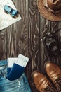 flat lay with denim pants, shoes, straw hat, retro photo camera, passports with tickets on dark