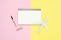 Top view mock up of blank white paper notebook, ball pen and airplane on pink and yellow pastel color screen. Royalty Free Stock Photo