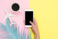 Flat lay design of travel in summer concept - Top view mockup of hand hold on smartphone, plane, leaf and coffee on pink yellow Royalty Free Stock Photo