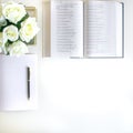 Flat lay with different accessories; flower bouquet, pink roses, open book, Bible