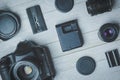 Flat lay with different black photoaccessories on light boards: camera, lenses, battery, charger, synchronizer, and lens covers Royalty Free Stock Photo