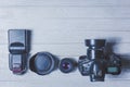 Flat lay with different photoaccessories arranged on white boards: camera, lenses, battery, charger, synchronizer, and lens covers Royalty Free Stock Photo