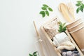 Flat lay eco-fiendly bags, paper cups, bamboo cutlery, galss water bottle with green leaves on white background