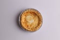 Flat lay of an egg tart in an aluminum foil tray isolated on a white background