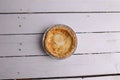 Flat lay of an egg tart in an aluminum foil tray isolated on a white rustic background