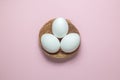 Flat lay of eggs in nest on plain pink background