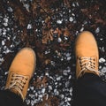 Feet of traveler in boots standing on ground, square crop